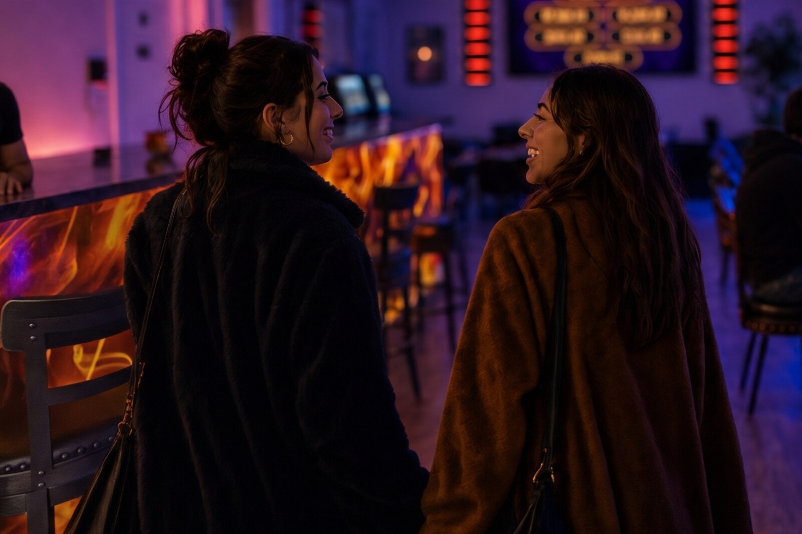 Two friends walk into The Flame together, sharing a laugh in the warm neon glow