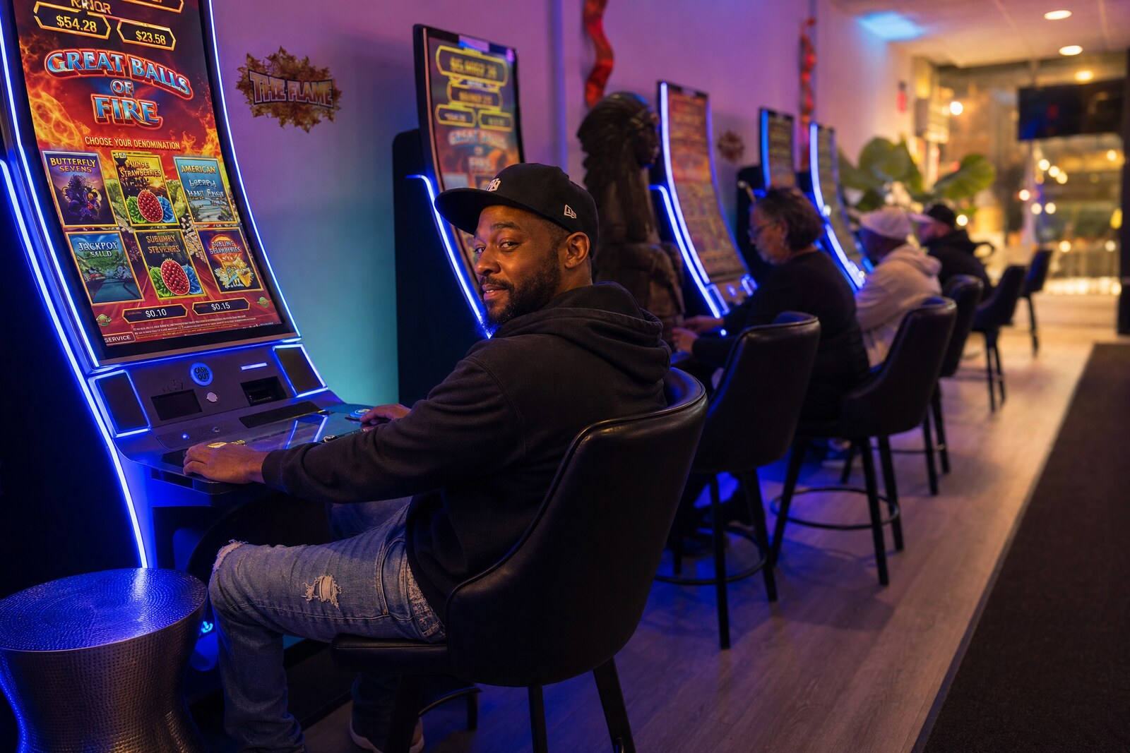 A man in a cap and hoodie glancing up with a relaxed smile at his machine as he unwinds